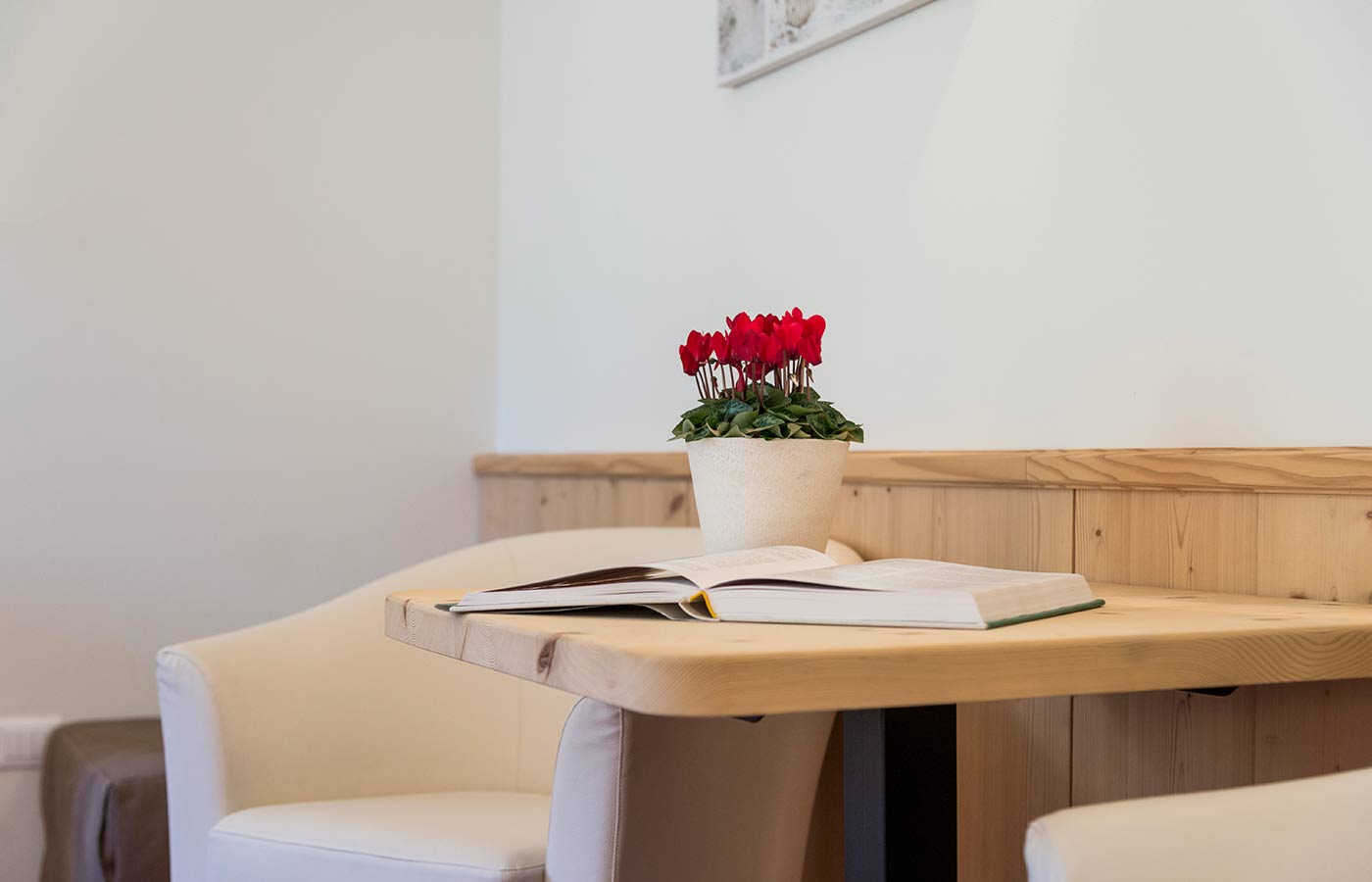 Tavolino in legno con vaso di fiori e libro aperto nella stanza dell'Hotel Waldheim